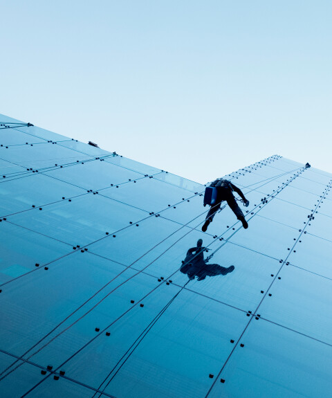 Low angle shot two persons rappelling side tall building